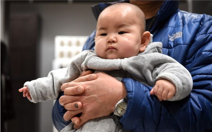 Un père tient son enfant dans ses bras dans un magasin de meubles à Pékin, le 19 janvier 2015. (Goh Chai Hin/AFP/Getty Images)