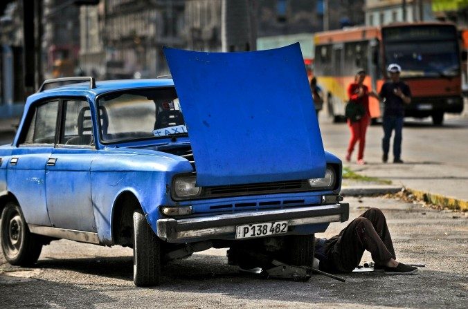 Un homme répare sa voiture à La Havane, le 11 janvier 2016. Un tiers des voitures à Cuba sont endommagées et circulent sur des routes en très mauvais état. (YAMIL LAGE / AFP / Getty Images)