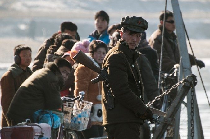 Un soldat nord-coréen monte la garde sur un bateau avec ses compatriotes sur la fleuve Yalu, à la frontière entre la ville nord-coréenne de Sinuiju et la ville chinoise de Dandong, le 9 février 2016. (JOHANNES EISELE / AFP / Getty Images)

