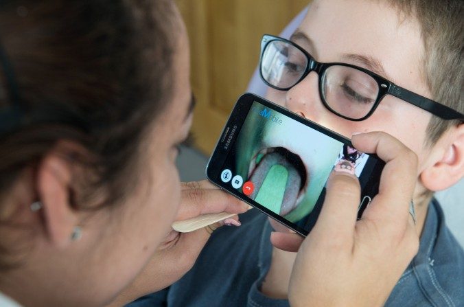 En passant par le téléphone intelligent que tient une infirmière, le Dr Thierry Castera examine la gorge d’un enfant lors d’une consultation médicale numérique à Oberbruck, en France, en septembre 2016. (Sebastien Bozon/AFP/Getty Images)
