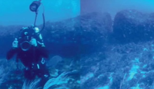 Un plongeur en face du monolithe de 15 tonnes dans le canal de Sicile. Il mesure au total 12 mètres de long, mais le bloc est cassé au milieu. (YouTube Capture d' écran / Le Cosmos Nouvelles)