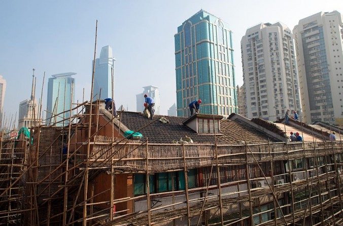 Les ouvriers rénovent le toit d'un immeuble résidentiel à Shanghai, le 21 août 2014. (JOHANNES EISELE / AFP / Getty Images)


