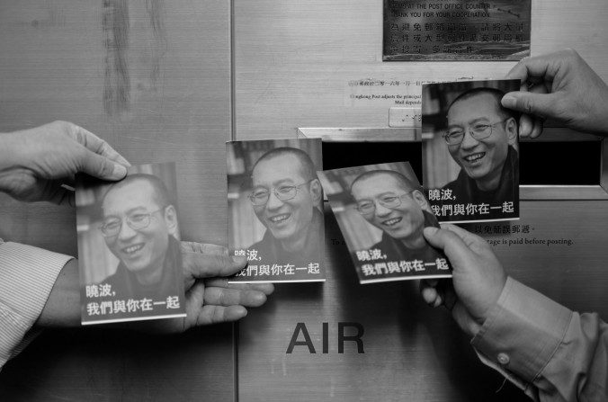 Des manifestants se préparent à poster des cartes-postales pour le dissident et Prix Nobel chinois Liu Xiaobo (en photo sur les cartes), devant un bureau de poste à Hong Kong, le 5 juillet 2017. Liu Xiabao, qui souffrait d'un cancer du foie, est décédé le 13 juillet 2017. (Anthony Wallace / AFP / Getty Images)