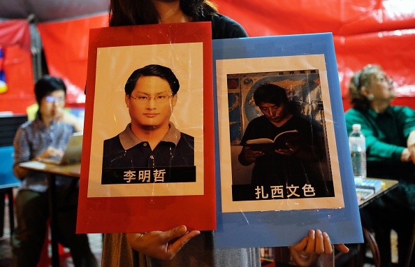 Un manifestant tient une pancarte avec la photo de l'activiste taïwanais Lee Ming-cheh et de l'avocate tibétaine Tashi Wangchuk à Taipei le 4 juin 2017, lors du 28e anniversaire du massacre de Tiananmen. (SAM YEH/AFP/Getty Images)