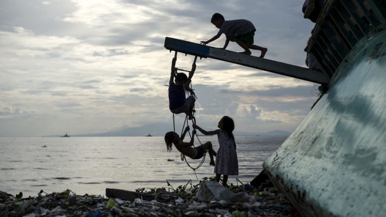 Des enfants philippins jouent avec un bateau de pêche échoué dans la baie de Manille remplie de déchets. (Noel Celis/AFP/Getty Images)