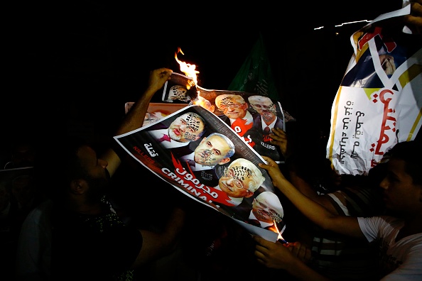 Des Palestiniens de Gaza brûlent des posters montrant les portraits de (de G à D) le ministre israélien de la Défense Avigdor Lieberman, le Premier ministre israélien Benjamin Netanyahu, le président palestinien Mahmoud Abbas et son Premier ministre Rami Hamdallah, couverts d'empreintes de chaussures militaires lors d'une manifestation à Gaza le 14 juillet dernier.
(MOHAMMED ABED/AFP/Getty Images)
