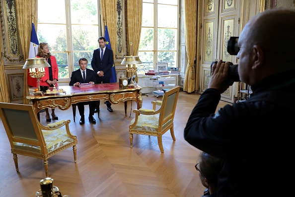 Le Président Emmanuel Macron, accompagné de la ministre de la Justice  Nicole Belloubet et du porte parole du gouvernement Christophe Castaner, signe, devant les caméras de direct de la télévision, les documents promulguant les lois sur la confiance dans la vie politique le 15 septembre à son bureau de l'Élysée. (LUDOVIC MARIN/AFP/Getty Images)