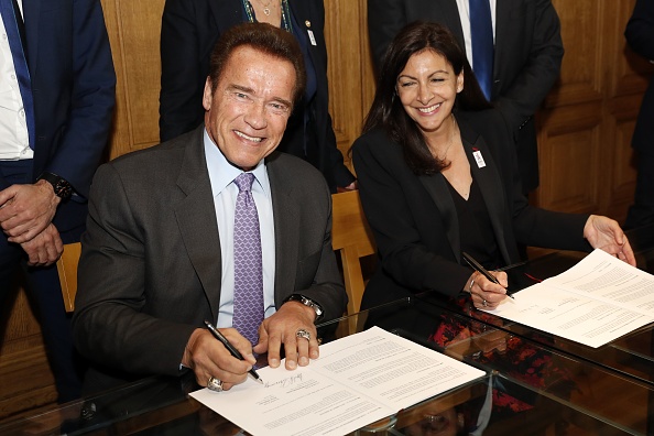 Arnold Schwarzenegger (G), ancien sénateur de l'État de Californie et président de l'organisation à but non lucratif «Regions of Climate Action» (R20), et Anne Hidalgo, maire de Paris, signent des documents le 28 avril 2017 à Paris dans le cadre d'une réunion Convention de coopération entre le C40 Cities Climate Leadership Group et l'organisation R20. (PATRICK KOVARIK / AFP / Getty Images)