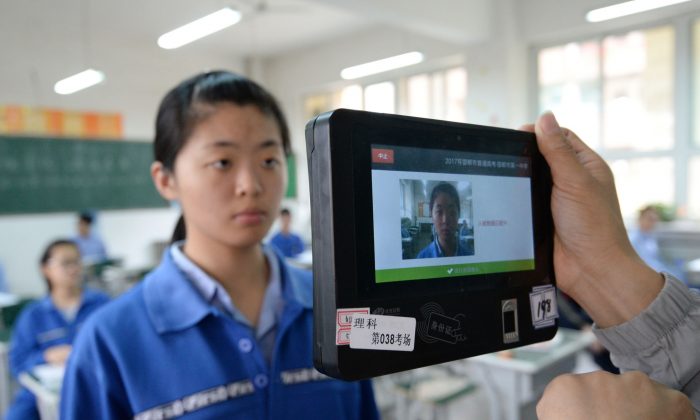 La technologie de reconnaissance faciale se propage rapidement dans toute la Chine. Cette photo montre un enseignant utilisant une machine de reconnaissance faciale et d’empreintes digitales qui permet d’identifier la personne avant l’examen d'entrée dans la province du Hebei, le 6 juin 2017. (STR / AFP / Getty Images)