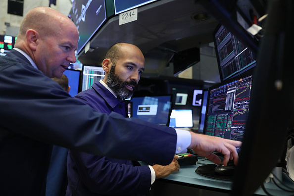 Des "traders" travaillent à l'étage de la Bourse de New York (NYSE) . En clôture de plus de 110 points, la moyenne Dow Jones des industries a poursuivi sa montée pour atteindre les 23 000 points pour la première fois. 
(Spencer Platt / Getty Images)