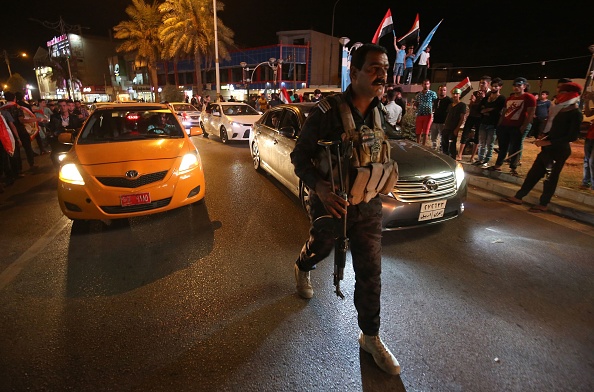Un policier irakien surveille le rassemblement des Irakiens dans la rue de Kirkouk le 18 octobre 2017, après que les forces gouvernementales irakiennes ont repris presque tout le territoire contesté entre Bagdad et la région kurde autonome, paralysant ses espoirs d'indépendance après un référendum controversé.(AHMAD AL-RUBAYE / AFP / Getty Images)