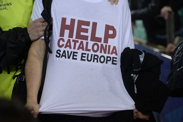 Un homme porte un t-shirt "aidez la Catalogne, sauvez l'Europe", est maintenu par le personnel de sécurité pendant le match de football du groupe D de l'UEFA Champions League FC Barcelona vs Olympiacos FC au stade Camp Nou à Barcelone le 18 octobre 2017. (JOSEP LAGO / AFP / Getty Images)