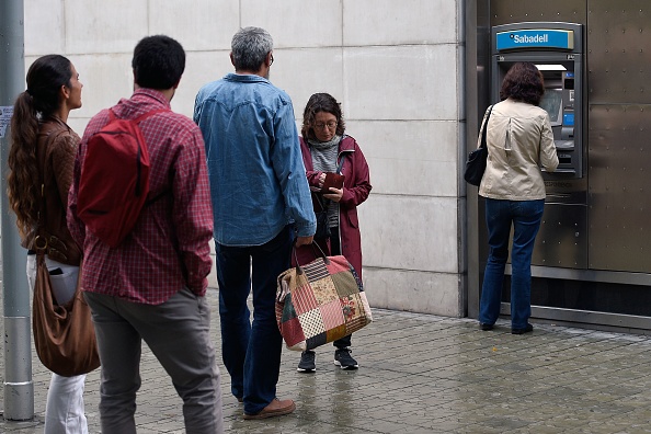 Des Catalans font la queue pour retirer des espèces à un distributeur de Banc Sabadell ATM le 20 octobre 2017 à Barcelone, en signe de protestation contre le gouvernement espagnol. (LLUIS GENE/AFP/Getty Images)