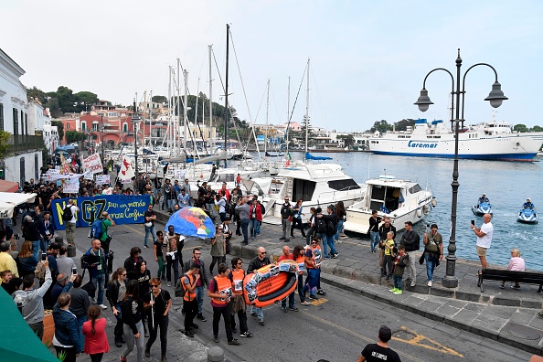 Des manifestants transportent un bateau en caoutchouc à leur arrivée dans le port de l'île italienne d'Ischia, pour symboliser les migrants morts en mer en traversant la Méditerranée.
(ANDREAS SOLARO / AFP / Getty Images)
