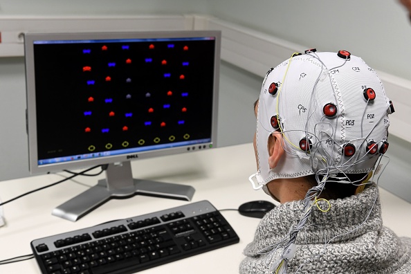Une photo prise le 20 novembre 2017 au GIPSA-lab au CNRS de Grenoble montre un chercheur utilisant un casque Brain-Computer-Interface 'Brain Invaders' qui permet de sélectionner des symboles sans commande moteur. Le casque détecte les signaux du cerveau avec des électrodes placées sur le cuir chevelu. 
(JEAN-PIERRE CLATOT / AFP / Getty Images)
