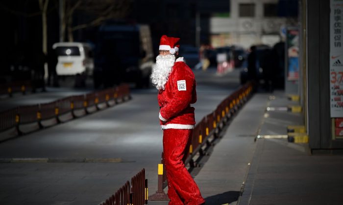 Un vendeur habillé en Père Noël attire les clients à l'entrée d'un magasin à Pékin, le 25 décembre 2014. (Wang Zhao / AFP / Getty Images)