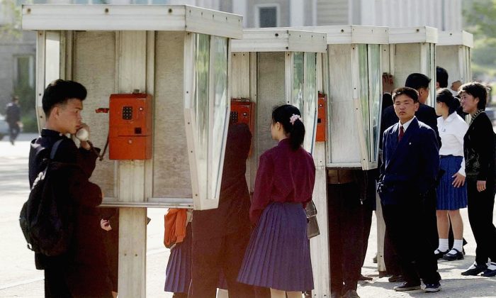 Des élèves nord-coréens utilisent un téléphone public après l'école, le 6 mai 2004, à Pyongyang, Corée du Nord. Les lignes fixes ont été fermées en Corée du Nord, peut-être à cause d'une fuite de l’annuaire du téléphone. Alors que l'utilisation du téléphone portable est répandue dans la capitale, les lignes fixes sont utilisées par les commerçants soucieux de leur budget et les entreprises d'État. Bon nombre de fonctionnaires et d’entreprises  ont du mal à communiquer. (Pool/Getty Images)