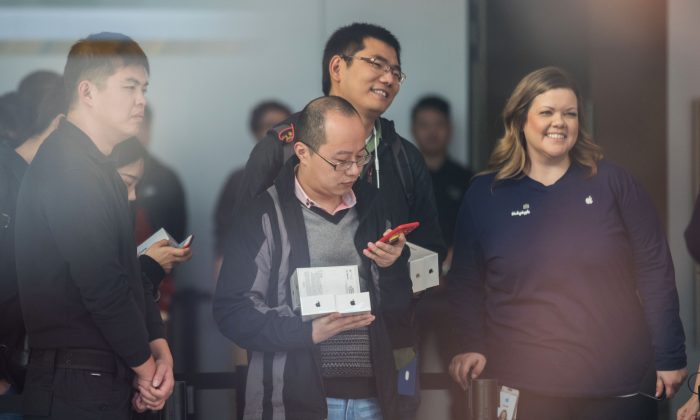 Des clients chinois font la queue dans un Apple store avec une employée étrangère d'Apple, dans la ville de Hangzhou, province du Zhejiang le 3 novembre 2017. (STR/AFP/Getty Images)
