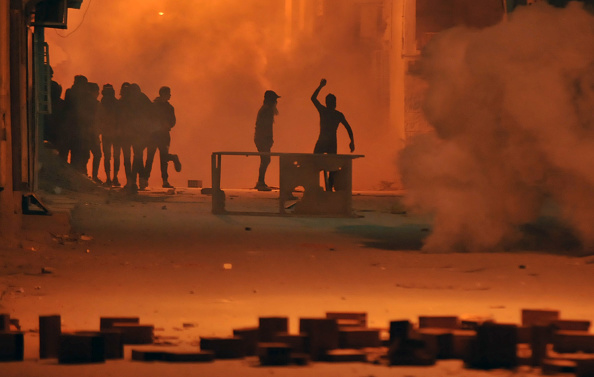 Les manifestants tunisiens ont jeté des pierres sur les forces de sécurité dans le district de Djebel Lahmer, à Tunis, tôt le 10 janvier 2018, après que les hausses de prix ont déclenché des manifestations dans le pays. Des échauffourées ont éclaté entre les manifestants et la police tunisienne, un jour après la mort d'un homme lors de violentes manifestations contre l'augmentation des coûts et l'austérité du gouvernement. Des centaines de jeunes sont descendus dans les rues de Tebourba, à l'ouest de Tunis, jetant des pierres sur les forces de sécurité qui ont riposté en tirant du gaz lacrymogène sur eux, a indiqué un journaliste de l'AFP. Des affrontements similaires ont été observés dans les régions intérieures pauvres de Kasserine et Jelma, près de Sidi Bouzid, berceau des manifestations qui ont déclenché les soulèvements du Printemps arabe en 2011. Des affrontements ont également éclaté dans la ville centrale de Gafsa, ont indiqué des journalistes de l'AFP.
(SOFIENE HAMDAOUI / AFP / Getty Images)