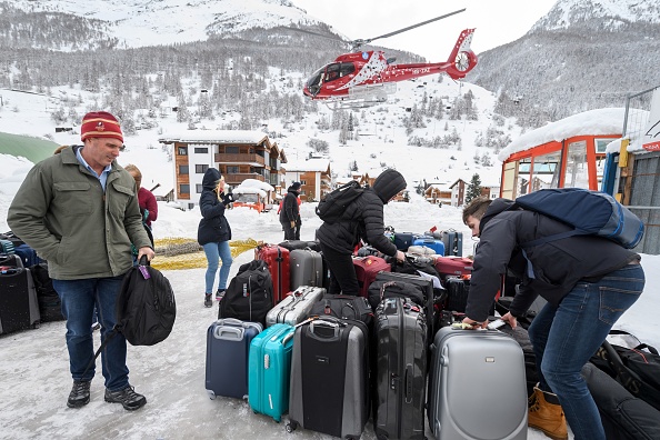 Les touristes évacuent la station de ski de Zermatt par hélicoptère le 10 janvier 2018 à Taesch, Alpes suisses. Les trains de la populaire station de ski suisse de Zermatt devraient rouvrir mercredi, apportant du secours à quelque 13 000 touristes bloqués par de fortes chutes de neige. "Les responsables travaillent dur pour la réouverture et sont confiants d'ouvrir le chemin de fer dans l'après-midi". 
(FABRICE COFFRINI / AFP / Getty Images)