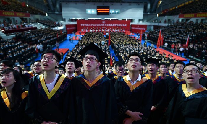 Les étudiants de l'Université Huazhong des Science et Technologie chantent lors de la cérémonie de remise des diplômes dans un stade de la ville de Wuhan, province du Hubei, le 20 juin 2017. (STR/AFP/Getty Images)