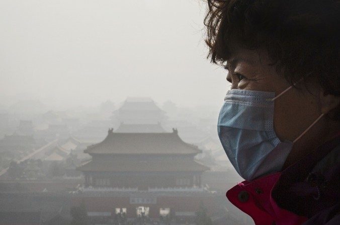 Une femme porte un masque à Pékin, près de la Cité interdite, sur laquelle s'est répandue un épais nuage de pollution, le 15 novembre 2015. (Kevin Frayer/Getty Images) 