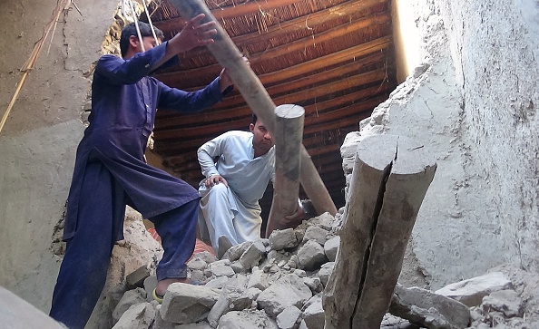 Des hommes afghans trient les décombres d'une maison endommagée par un tremblement de terre le 27 octobre 2015. Photo STR / AFP / Getty Images)