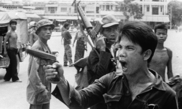 Un soldat khmer rouge brandit son pistolet et ordonne aux propriétaires de magasins d'abandonner leurs magasins à Phnom Penh, au Cambodge, le 17 avril 1975, lorsque la capitale est tombée aux mains des forces communistes. (AP Photo/Christoph Froehder)