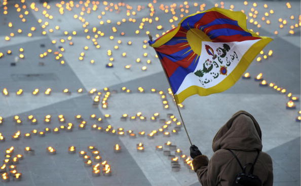 Une femme tient le drapeau tibétain à côté des bougies formant les mots « Tibet libre » lors d'une manifestation de soutien au Tibet et contre la violence dans la région chinoise. Photo FREDRIK SANDBERG/AFP/Getty Images.