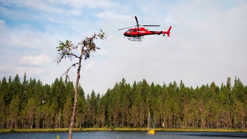 Les pompiers dans l’hélicoptère utilisent un lac local pour remplir ses réservoirs d'eau afin de s'attaquer à une forêt en feu à Korskrogen près de Ljusdal, en Suède, le 25 juillet 2018. photo JONATHAN NACKSTRAND / AFP / Getty Images.