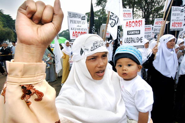 Une mère indonésienne tient son enfant en train de crier des slogans avec d'autres lors d'une manifestation anti-avortement devant le Palais présidentiel à Jakarta. Selon la loi, l'avortement en Indonésie est interdit sauf si la santé de la mère est en danger. Photo JEWEL SAMAD / AFP / Getty Images.