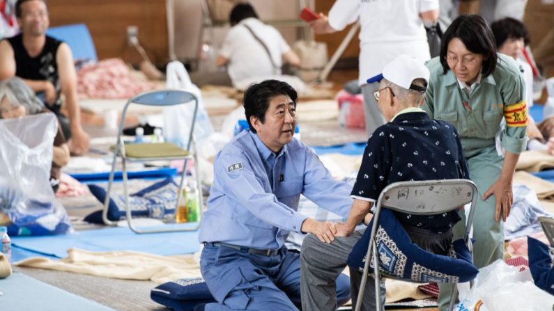 le Premier ministre japonais Shinzo Abe (C) visite un abri pour les personnes touchées par les récentes inondations à Mabi, préfecture d'Okayama, le 11 juillet 2018. - Le bilan des pluies record qui ont dévasté certaines régions du Japon est passé à 179, a déclaré le principal porte-parole du gouvernement le 11 juillet.  (MARTIN BUREAU/AFP/Getty Images)