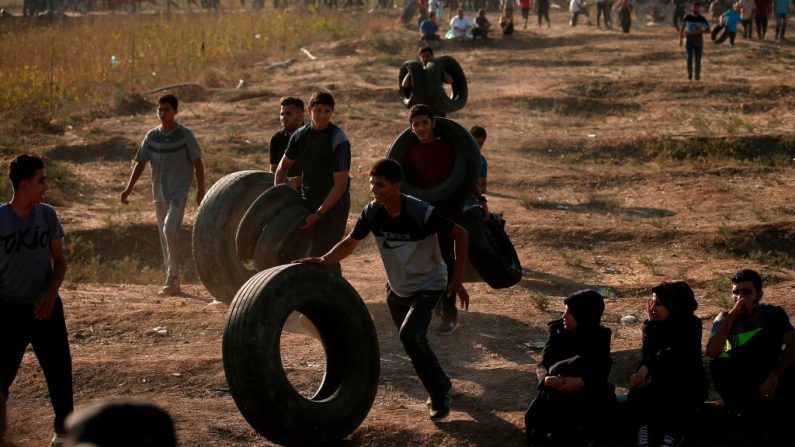 Des manifestants palestiniens portent des pneus à brûler lors d'une manifestation le 17 août 2018 le long de la frontière entre Israël et la bande de Gaza. Photo : MAHMUD HAMS / AFP / Getty Images.