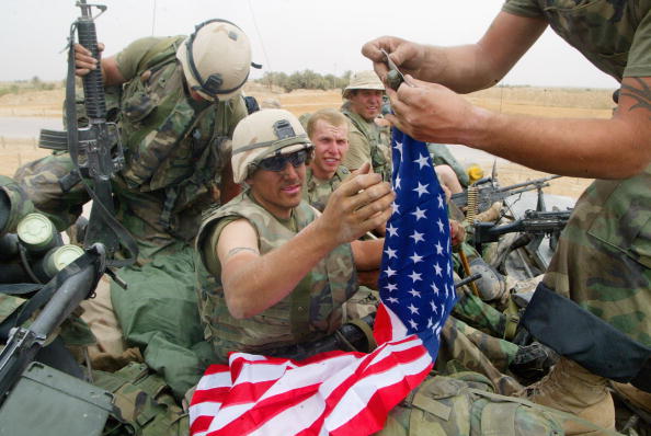 Les forces de la coalition traversent l'Irak. Le caporal américain Kristopher Ecker d'Irvington, et d'autres membres de la Force opérationnelle apposent un drapeau américain sur un poteau.Photo de Joe Raedle / Getty Images.