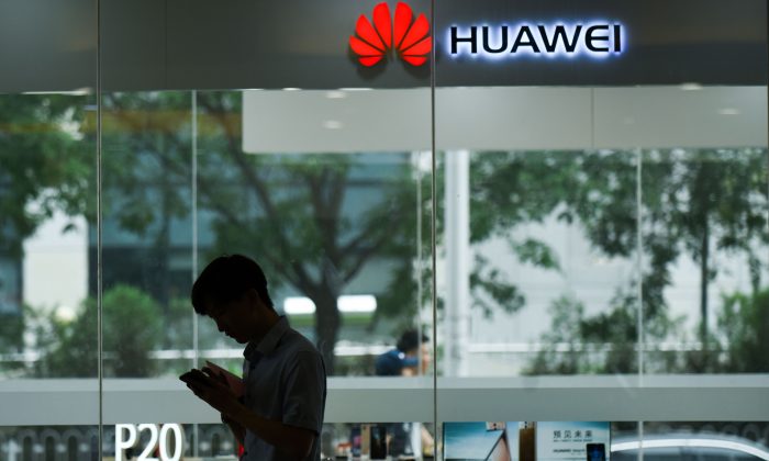 Un homme utilise son téléphone portable devant un magasin Huawei à Pékin le 7 août 2018. (Wang ZHAO / AFP / Getty Images)
