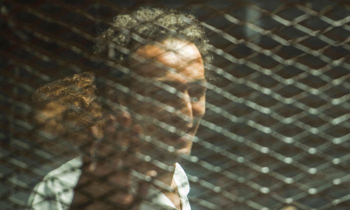 Le photojournaliste égyptien Mahmoud Abu Zeid, connu sous le nom de Shawkan, apparait sur le banc des accusés entouré de verre insonorisée pendant son procès dans la capitale du Caire, le 8 septembre 2018. (Mohamed el-Shahed/ AFP/Getty Images)