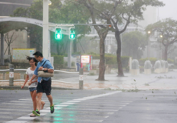 -Un couple traverse la rue dans le centre-ville de Naha, dans la préfecture d'Okinawa, le 29 septembre 2018 alors que le typhon Trami frappe le Japon : Photo JIJI PRESS / AFP / Getty Images.