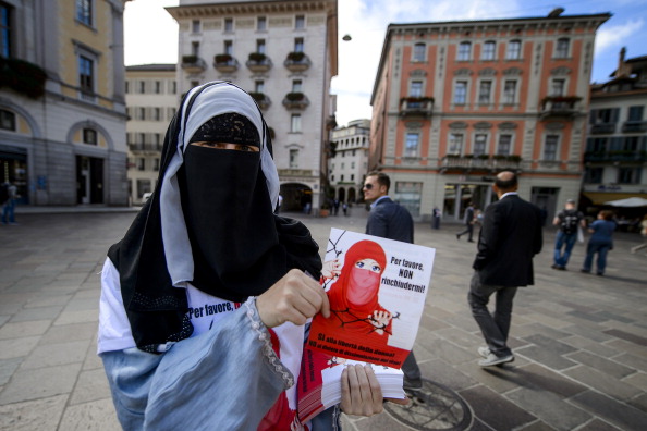 Une femme distribue des tracts sur lesquels on pouvait lire « S’il vous plaît, ne me laissez pas enfermer » sur l'interdiction des couvre-chefs couvrant le visage dans les lieux publics. Un vote a eu lieu le 22 septembre le premier canton suisse à organiser un référendum dit « anti-burqa ». Photo : FABRICE COFFRINI / AFP / Getty Images.