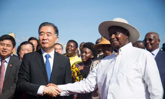 Le troisième vice-premier ministre chinois, Wang Yang (à gauche) et le président ougandais Yoweri Museveni (à droite) se serrent la main lors de la cérémonie d'inauguration de la voie express de 51 kilomètres, financée par la Chine, qui relie la capitale et l'aéroport international à Entebbe, Ouganda, le 15 juin 2018. (SUMY SADURNI/AFP/Getty Images)