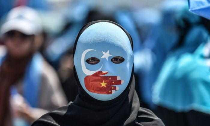 Un manifestant porte un masque peint aux couleurs du drapeau du Turkestan oriental et une main aux couleurs du drapeau chinois. (Photo : Ozan Kose/AFP/Getty Images)