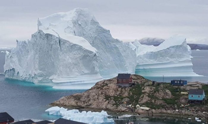 Un iceberg derrière des maisons et des bâtiments après qu'il s'est échoué à l'extérieur du village d'Innarsuit, une colonie insulaire dans la municipalité d'Avannaata au nord-ouest du Groenland. (Magnus Kristensen/AFP/Getty Images)