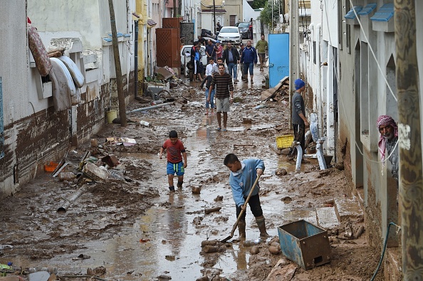 -Des personnes marchent dans une rue boueuse inondée par les pluies torrentielles dans la ville de Mhamdia, près de Tunis, la capitale tunisienne, le 18 octobre 2018. Des inondations soudaines en Tunisie ont tué au moins cinq personnes, tandis que deux autres sont disparues, a déclaré aujourd'hui le ministère de l'intérieur. Photo FETHI BELAID / AFP / Getty Images.