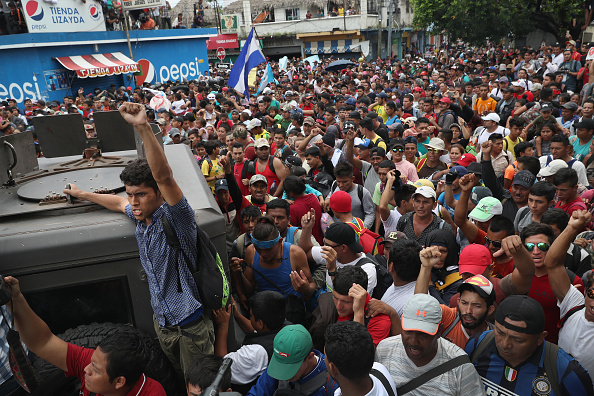 Des membres de la caravane de migrants avancent à une porte séparant le Guatemala du Mexique le 19 octobre 2018 à Ciudad Tecun Uman, au Guatemala. La caravane de milliers d'immigrants, originaires pour la plupart du Honduras, a ouvert la porte du côté guatémaltèque et a traversé le pont en direction du Mexique, avant d'être repoussée par la police anti-émeute mexicaine.(Photo : John Moore/Getty Images)