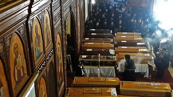 -Des membres du clergé égyptien se tiennent près des cercueils des victimes de l'explosion d'une bombe qui avait visé une église copte orthodoxe la veille au Caire, lors de leurs obsèques dans le quartier de Nasr City, le 12 décembre 2016. Photo KHALED DESOUKI / AFP / Getty Images.