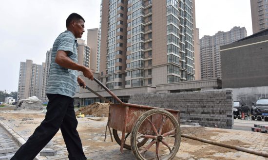 Un ouvrier pousse une charrette sur le chantier d'un complexe de logements à Pékin, le 15 août 2017. (Greg Baker/AFP/Getty Images)