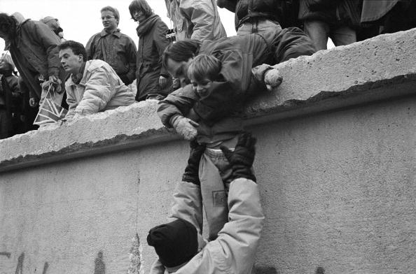 Les Berlinois de l'Est grimpent sur le mur de Berlin pour célébrer la fin effective de la partition de la ville, le 31 décembre 1989. Steve Eason/Hulton Archive/Getty Images


