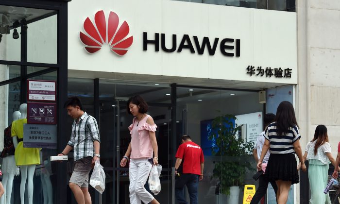Des gens passent devant un magasin Huawei à Pékin. Le géant chinois de l'équipement de télécommunications domine le marché de la technologie sans fil 5G, dans le cadre des objectifs de Pékin pour atteindre l'autonomie technologique. (Greg Baker/AFP/Getty Images)