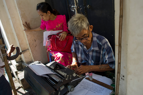 -Cette photo prise le 5 décembre 2018 montre la dactylo Aung Min travaillant sur un document d'un client avec son ancienne machine à écrire le long de la rue Pansodan à Rangoun. Des nettoyeurs d'oreilles, des plombiers travaillant au bord des routes et des machines à écrire à la location, le cœur palpitant de la plus grande ville du Myanmar où des emplois désuets subsistent malgré des changements imparables. Photo YE AUNG THU / AFP / Getty Images.