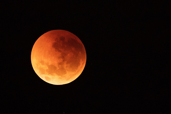 -On voit la lune virer au rouge sur l'horizon de Sydney lors d'une éclipse lunaire totale le 28 juillet 2018 en Australie. L’éclipse lunaire est la plus longue du 21e siècle et dure 1 heure et 43 minutes. Photo de Cameron Spencer / Getty Images.