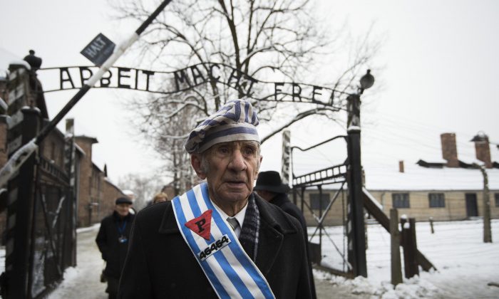 Miroslaw Celka, un survivant d'Auschwitz, sort de la porte du camp de la mort avec l'écriteau « Le travail vous libère », le 27 janvier 2015, jour du 70e anniversaire de la libération de l'usine d'extermination nazie dans le sud de la Pologne. (Images impaires d'Andersen/AFP/Getty)